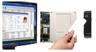 A computer monitor displaying software with a person’s photo and information. Next to it is an open panel showing electronic components, illustrating an intricate access control system. A hand holds a card near a card reader device, demonstrating the security features in use.