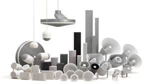 A collection of variously shaped and sized gray and white audio speakers and components, suitable for a public address system, is displayed against a white background. The group includes cylindrical, spherical, and rectangular forms in wall-mounted, freestanding, and pendant styles.