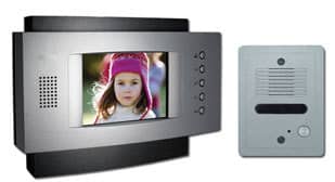 A home intercom system is shown. The video door phone consists of a main unit with a screen displaying a young child wearing a pink hat, and a secondary unit featuring a speaker and a button. The main unit has several buttons and a side speaker.